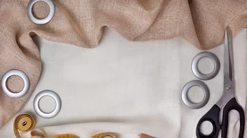 Stoff zum Nähen von Vorhängen. Stoff, Schere, Maßband, Ringe auf einem leichten Stoff.